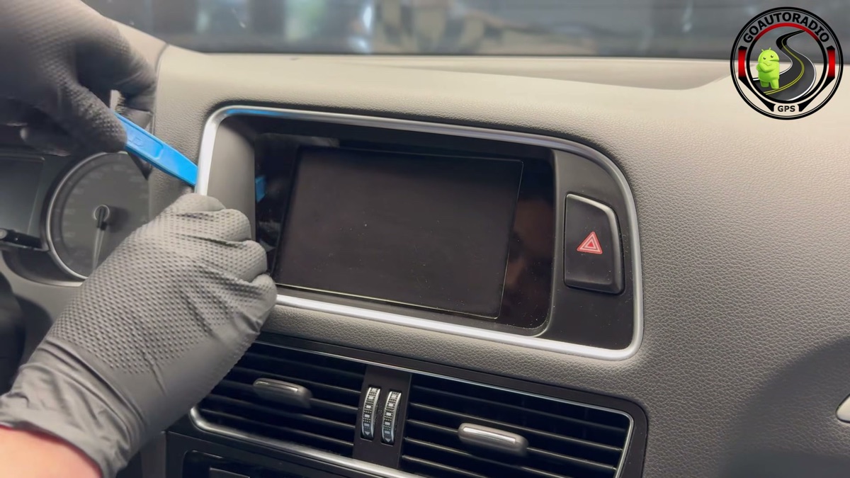 Démontage de la façade autour de l'écran Audi Q5 avec un outil plastique